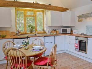 a kitchen with a table and chairs and a kitchen with white cabinets at High House Holiday Cottages 1 in Hooe