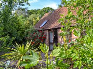 a brick house surrounded by trees and plants at High House Holiday Cottages 1 in Hooe