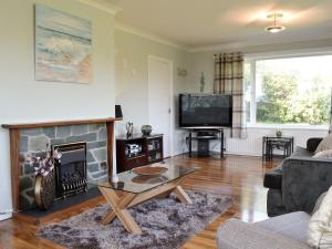 a living room with a fireplace and a tv at Encil-y-mor in Criccieth