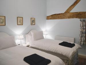 two beds in a bedroom with white sheets and black towels at Barley House - RFFN in Fownhope