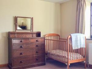 1 dormitorio con cuna y tocador con espejo en The Pump House, en Hawkesbury