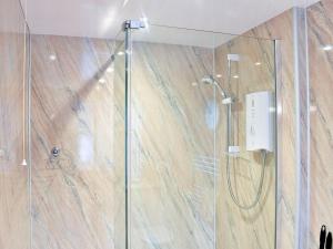 ducha con puerta de cristal y pared de madera en Strand Cottage, en Seahouses