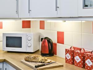 a microwave oven sitting on a counter with a cutting board at Rose Cottage - 28176 in Fairgirth