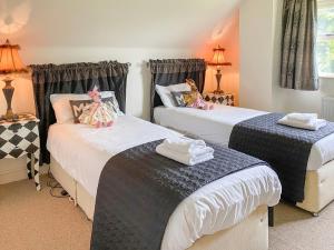 a room with two beds and two tables with lamps at Storrs Croft in Arkholme