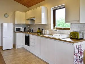 a kitchen with white cabinets and a white refrigerator at Hawthorn Lodge in Burgh le Marsh