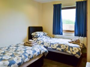 a bedroom with two beds and a window with blue curtains at Hawthorn Lodge in Burgh le Marsh