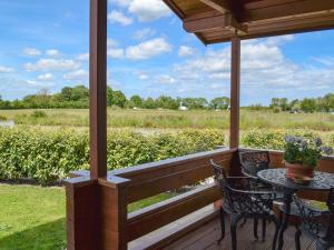 a porch with a table and chairs and a view of a field at Hawthorn Lodge in Burgh le Marsh