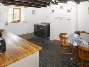 La cocina está equipada con fogones, mesa, mesa y vajilla. en Garden Cottage, en Onecote