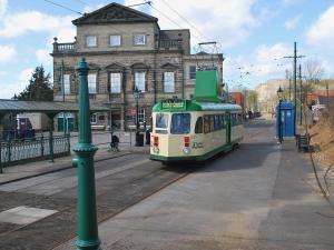 a green and white tram on a street in front of a building at Garden Cottage in Onecote