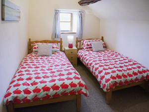 a bedroom with two beds with red and white covers at Garden Cottage in Onecote