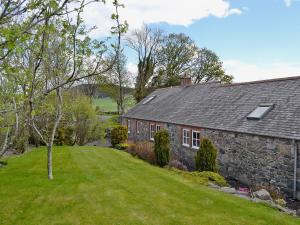 an old stone house with a green yard at The Wee Byre in Shawhead