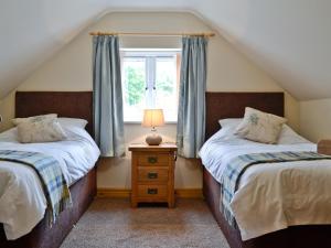 a attic bedroom with two beds and a window at Bwthyn Bwlch in Denbigh