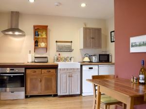 uma cozinha com armários de madeira e uma mesa de madeira em The Writing Room em Barford