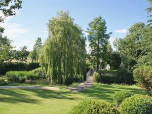 a park with a weeping willow tree and a path at The Writing Room in Barford