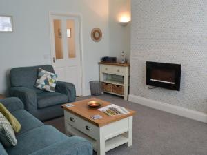 a living room with a couch and a table and a tv at Kittiwakes in Amble