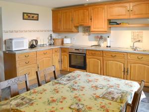 a kitchen with wooden cabinets and a table with a table cloth at Burnoon Barn in Cury