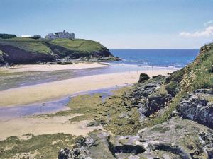 a beach with a castle on a hill next to the ocean at Burnoon Barn in Cury