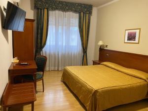 a bedroom with a bed and a desk and a television at Hotel Il Vigneto in Gattinara