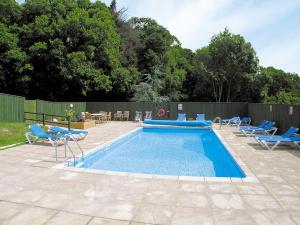 uma piscina com cadeiras azuis e uma cerca em Honey Pippin em Cheriton Bishop