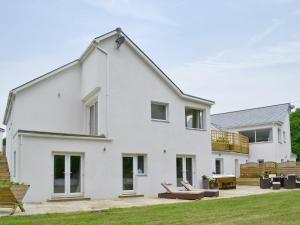 a white house with a patio and a deck at Honey Pippin in Cheriton Bishop