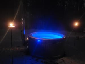 a hot tub with a blue light in the dark at Agro Breza domek nad samym jeziorem- sauna, balia ogrodowa in Lipusz