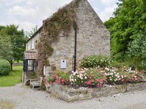 um velho edifício de pedra com flores em frente em Mill Cottage em Rievaulx