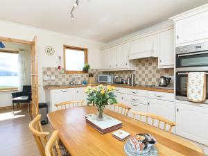 a kitchen with a wooden table with a vase of flowers on it at Ach-na-clachan in Gairloch