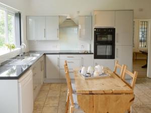 una cocina con mesa de madera y una cocina con armarios blancos. en Silverdale en Bacton
