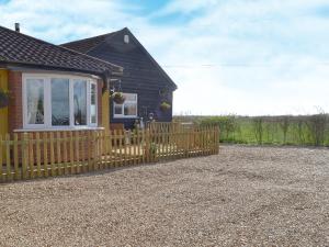 a house with a wooden fence in front of it at Reed Lodge in Littleport