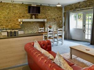 a living room with a leather couch and a kitchen at Rosecraddoc Manor - Stable in Saint Cleer