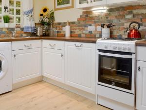 a kitchen with white cabinets and a stove at Reed Lodge in Littleport