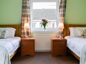 オーバンにあるHarbour Viewのベッドルーム1室(ベッド2台付)、花瓶のある窓が備わります。