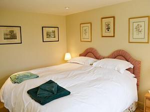 Un dormitorio con una cama blanca con una caja verde. en Reids Cottage, en Lairg