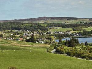 a green field with a town and a river at Reids Cottage in Lairg