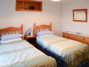 a bedroom with two beds and a mirror on the wall at Stable Cottage in John O Groats