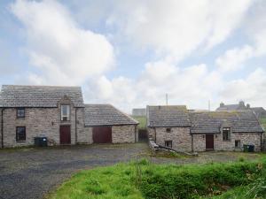zwei alte Steingebäude auf einem Grasfeld in der Unterkunft Stable Cottage in John O Groats
