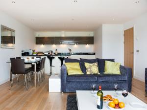 a living room and kitchen with a blue couch at Fistral View - 3 Cribbar in Newquay