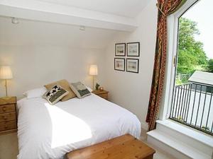 a bedroom with a white bed and a window at Wee Bridge Farm Cottage in Mobberley