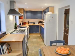 a kitchen with blue cabinets and a white refrigerator at Dyes Cottage in Hindolveston