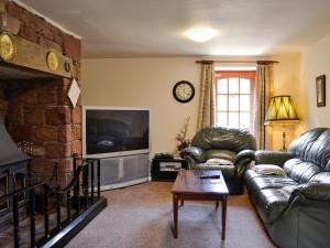 a living room with a leather couch and a tv at The Maltings in Beckfoot