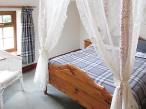 a bedroom with a bed with a canopy and curtains at The Maltings in Beckfoot