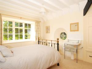 a bedroom with a bed and a desk and a window at Bishops View in Polzeath