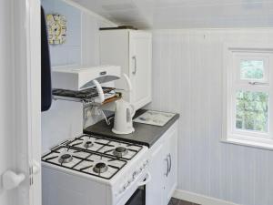 uma cozinha branca com um fogão forno superior ao lado de uma janela em Learig Cottage em Maidens