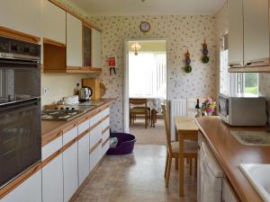 a kitchen with white cabinets and a table in it at Dart Corner in Bovey Tracey