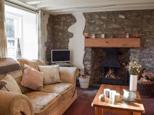 a living room with a couch and a fireplace at Woodlands Cottage in Freystrop