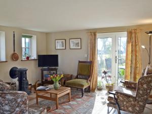 uma sala de estar cheia de mobiliário e uma televisão em Honeypot Cottage em Saint Cross