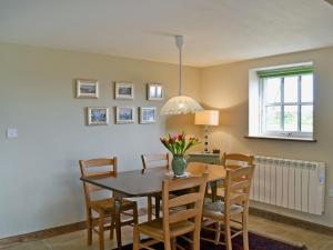 uma sala de jantar com uma mesa de madeira e cadeiras em Honeypot Cottage em Saint Cross