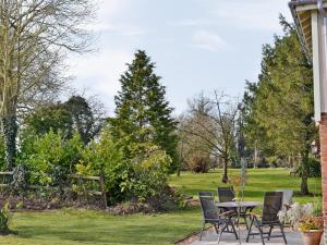 een patio met een tafel en stoelen in een tuin bij Honeypot Cottage in Saint Cross