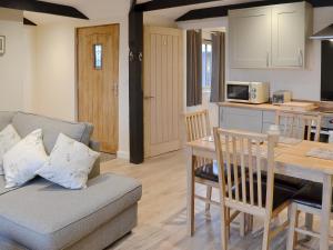 a living room and kitchen with a couch and a table at Dairy Cottage in Alkham