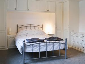 a bedroom with a bed with white walls and a dresser at Tower House in Ambleside